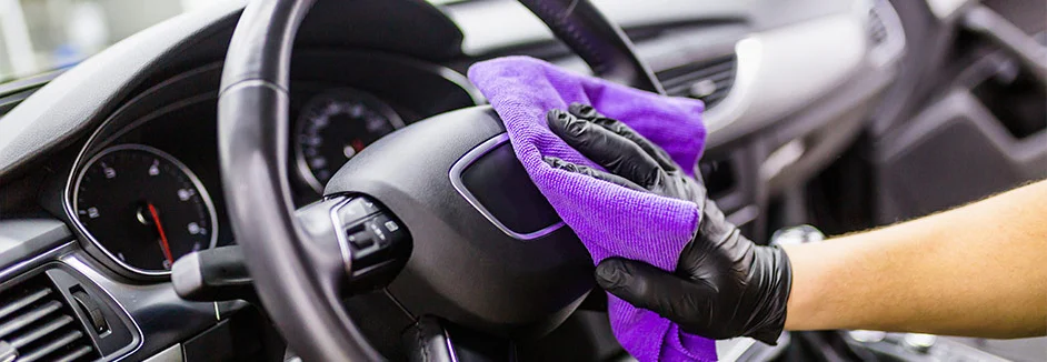 Hand reinigt Lenkrad mit Tuch